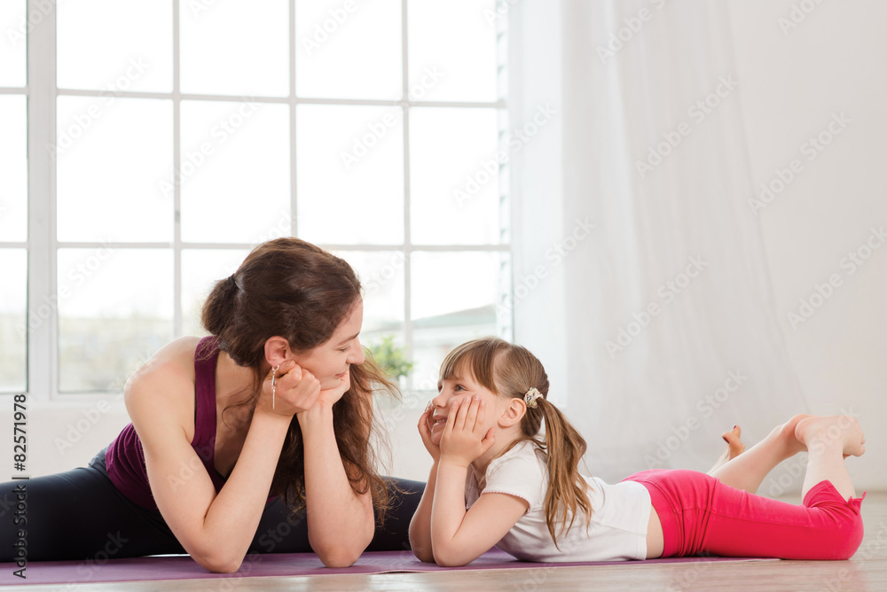 年轻母亲在瑜伽运动中与女儿交谈