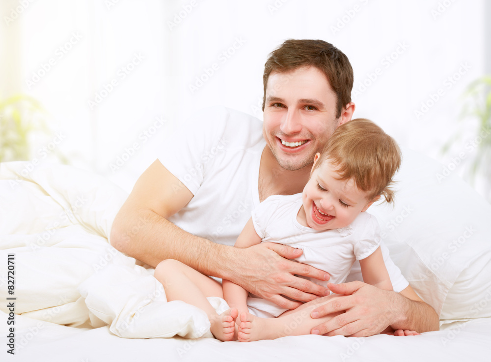 快乐的家庭父亲和宝贝女儿在床上玩耍