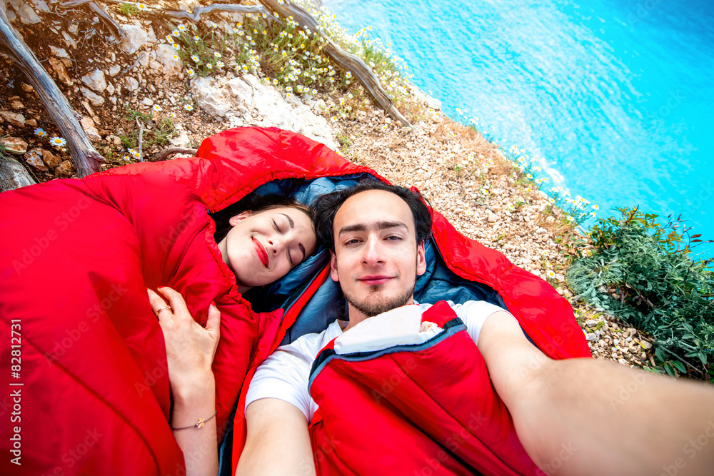 Young couple in sleeping bags near the sea
