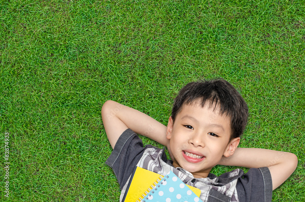 亚洲男孩微笑着躺在草地上的俯视图