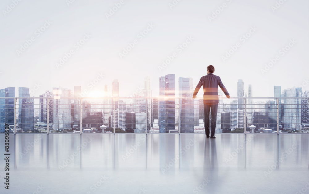 Businessman standing on a roof and looking at sunset