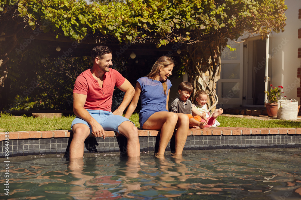 快乐的年轻家庭在泳池附近享受