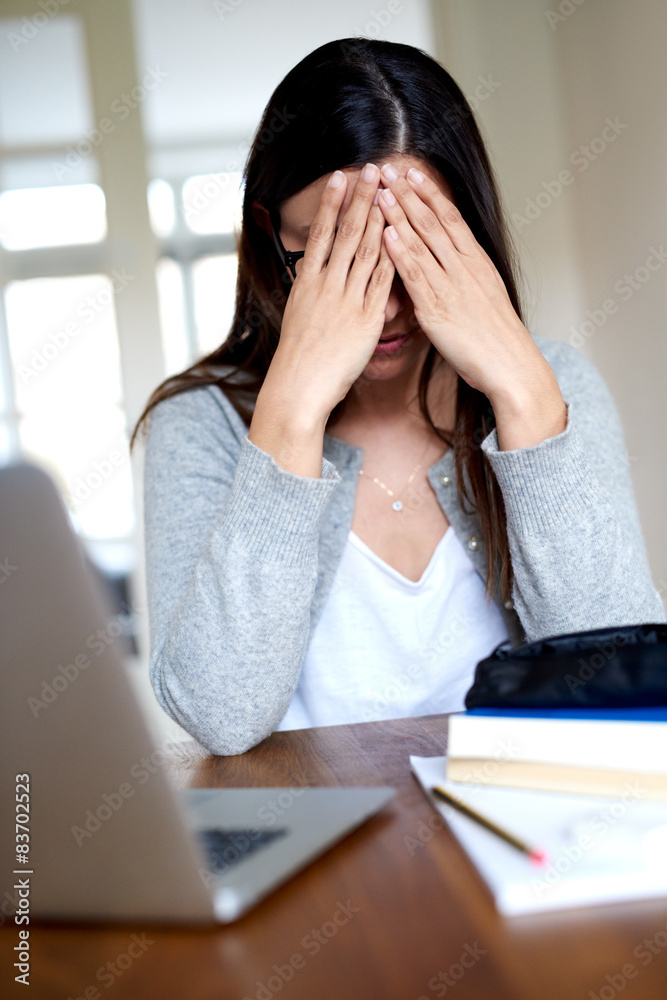 一个双手抱头坐在办公桌前的女人。