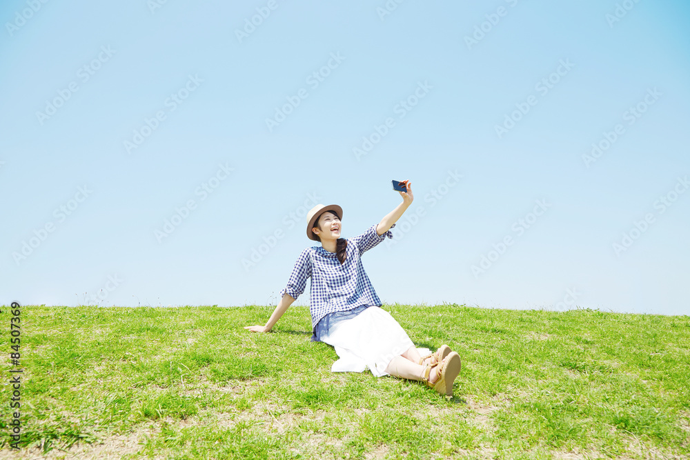 外でスマートフォンで自撮りする女性