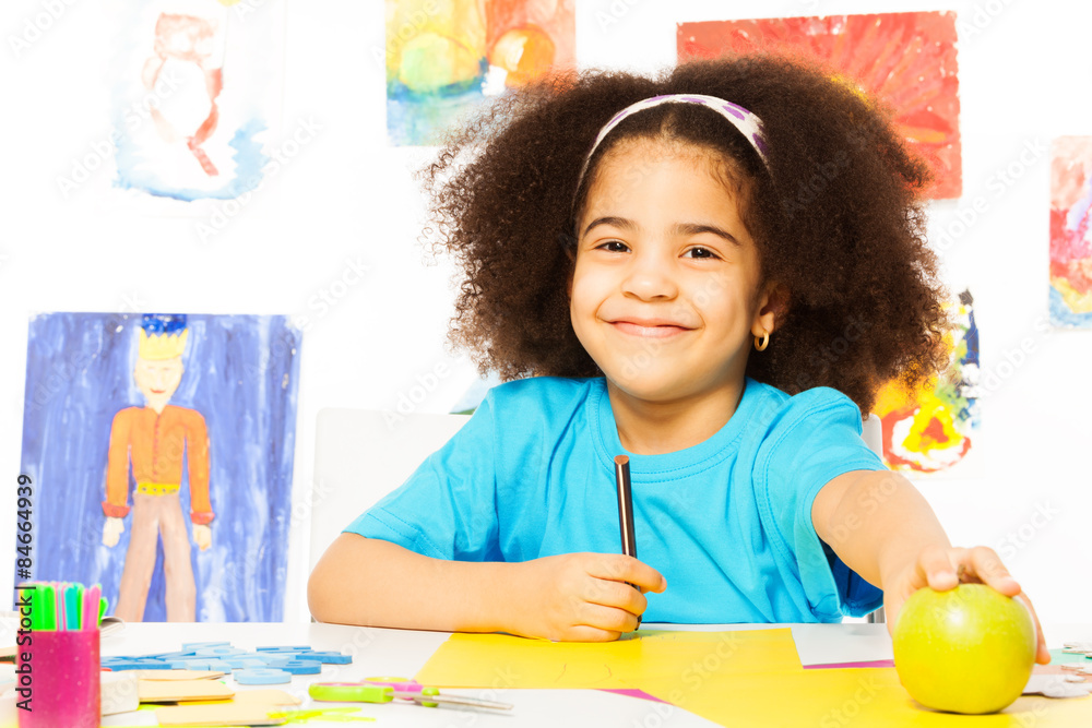 微笑的非洲女孩拿着铅笔和苹果