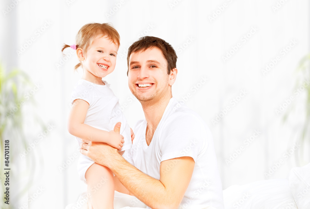 Happy family father and baby  daughter playing in bed