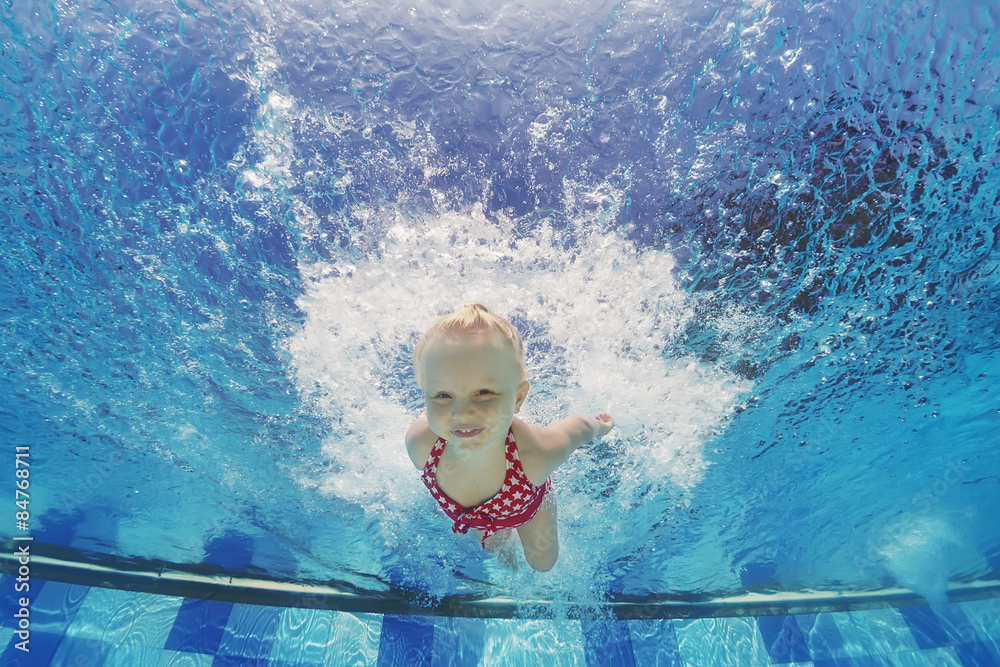 Baby girl swimming and diving in pool with fun - jumping deep down underwater with splashes Active l