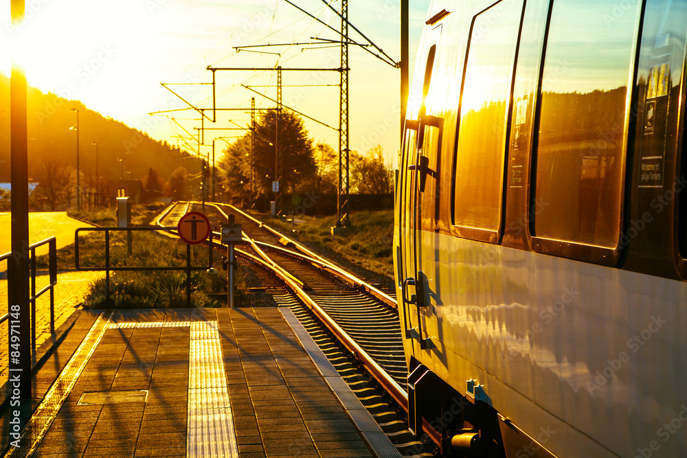 日落时分，现代客运列车停靠在风景秀丽的乡村站台。