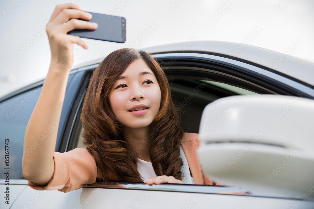 亚洲女性坐在车里使用手机摄像头