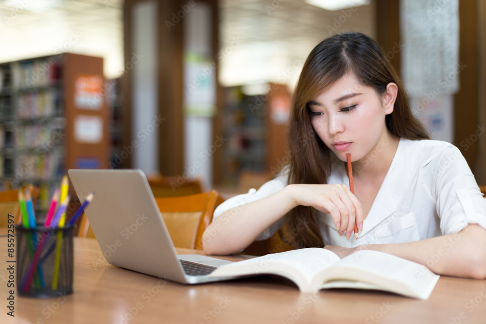亚洲美女女学生在图书馆用笔记本电脑学习