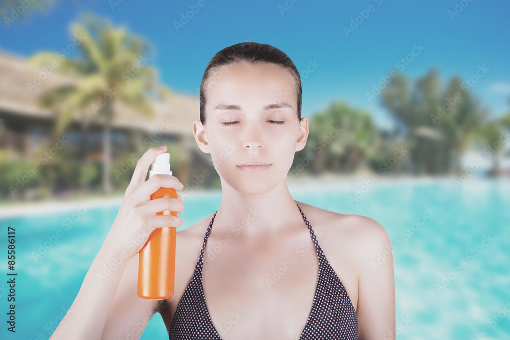 Donna spruzza crema su viso in costume sfondo piscina