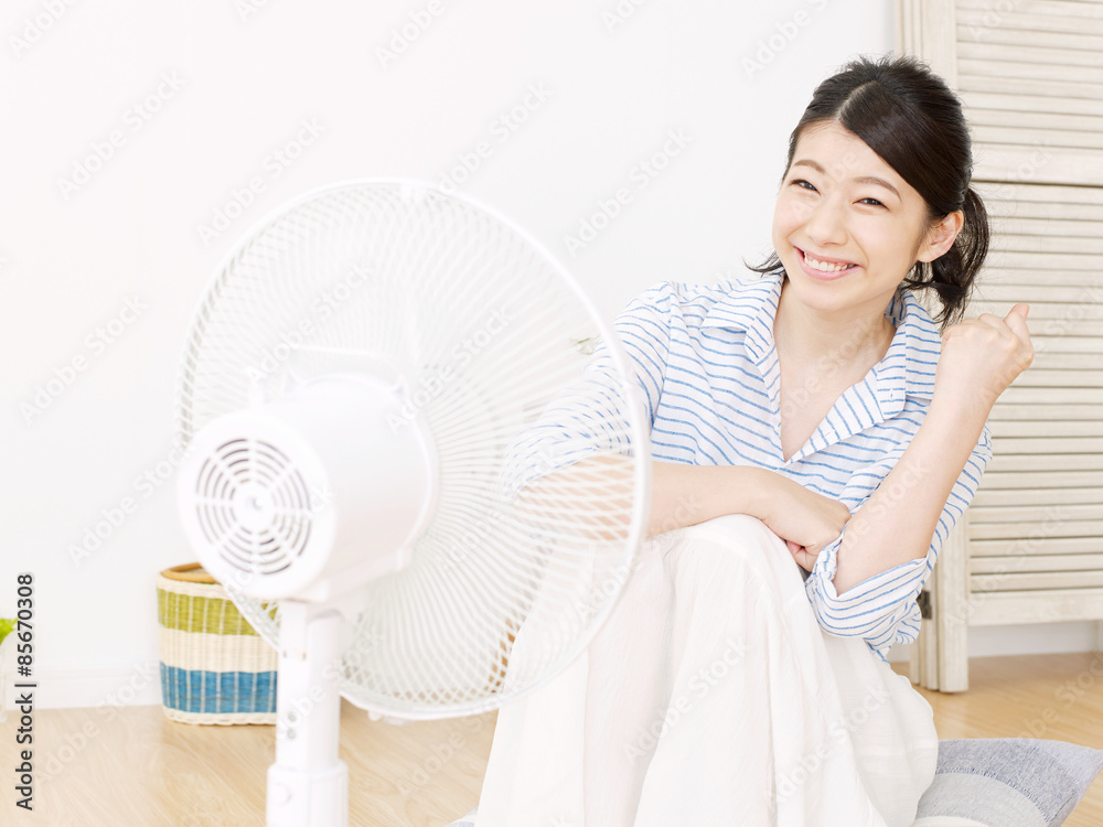 扇風機で涼む女性　ガッツポーズ