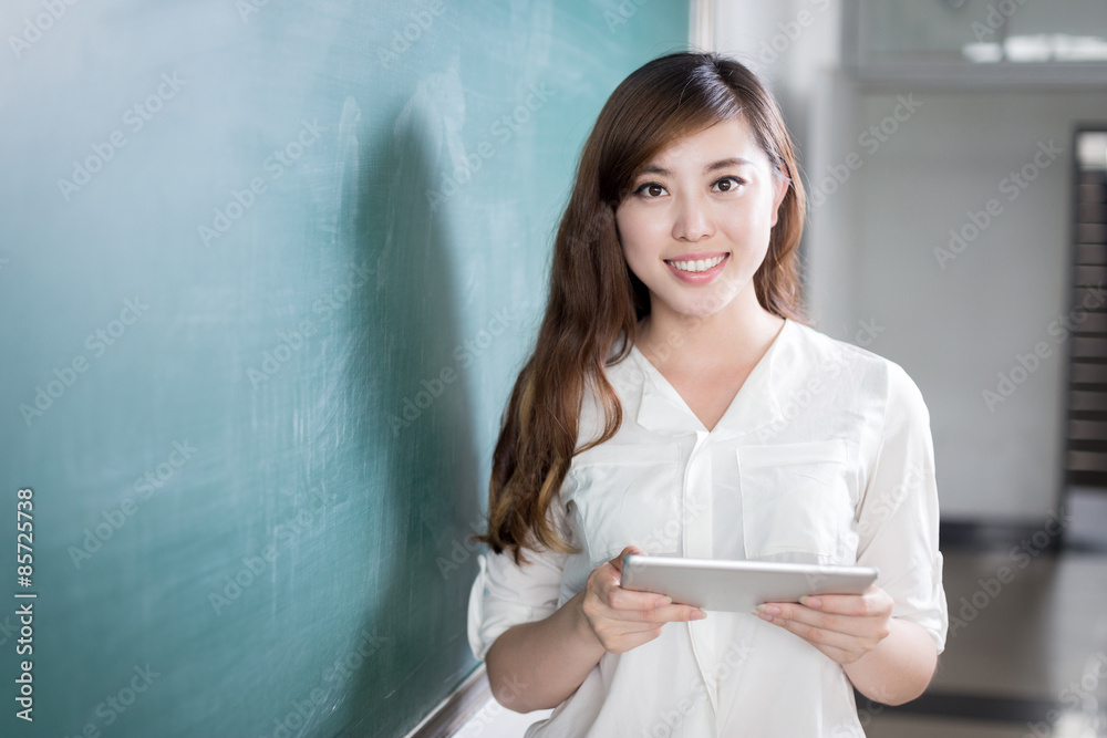亚洲美女在黑板前拿着平板电脑