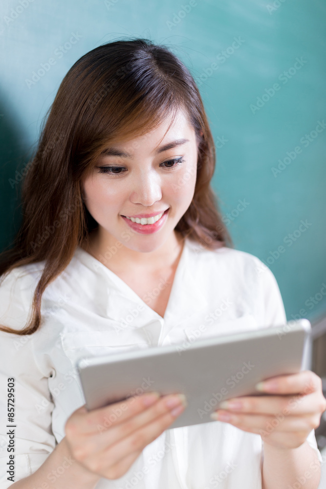 亚洲美女在黑板前拿着平板电脑