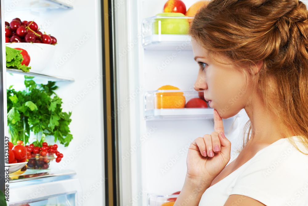 快乐的女人和打开的冰箱里有水果、蔬菜和他