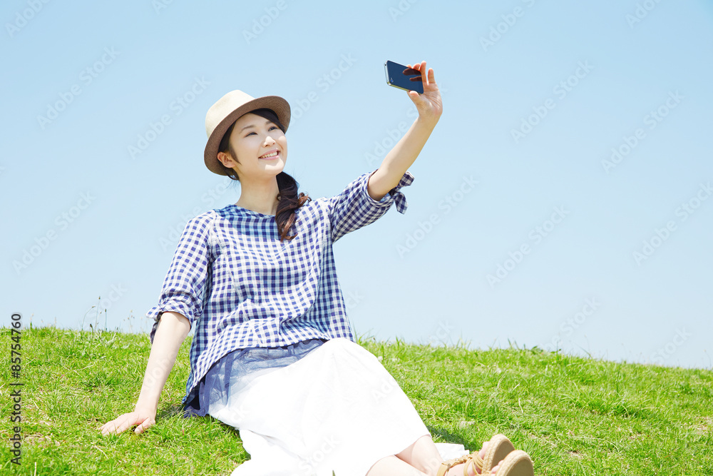 外でスマートフォンで自撮りする女性