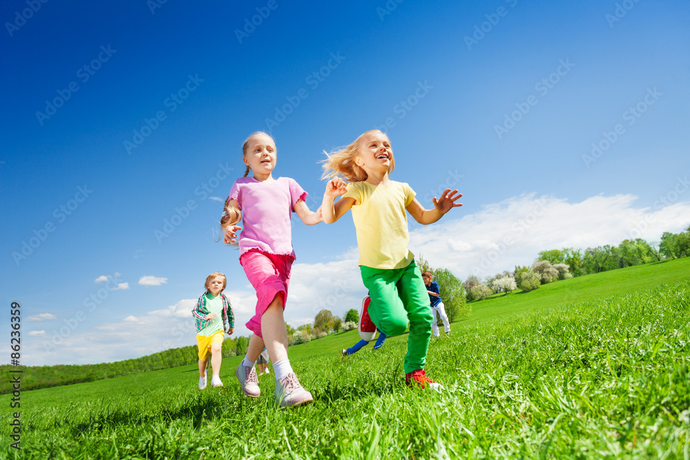 快乐的女孩和其他孩子在绿地上奔跑