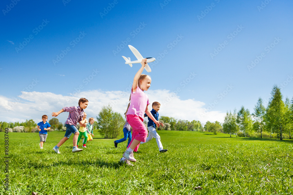 小女孩拿着飞机玩具，孩子们在奔跑