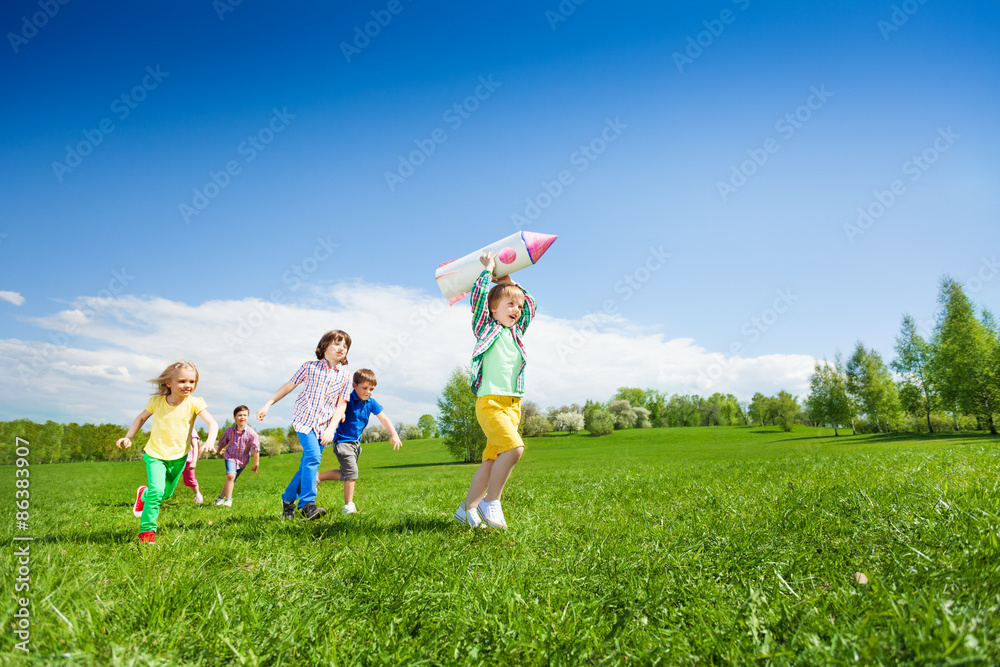 孩子们追着拿着火箭纸箱玩具的男孩跑