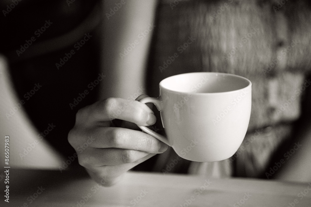 Cup of tea in woman hand, b&w with film grain 