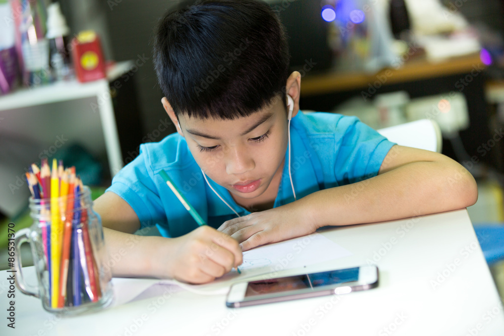 亚洲男孩用手机在白纸上画画