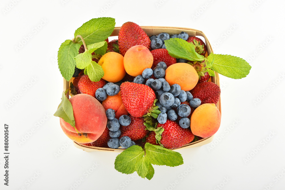 Strawberries, apricots, blueberries, peach in basket isolated on