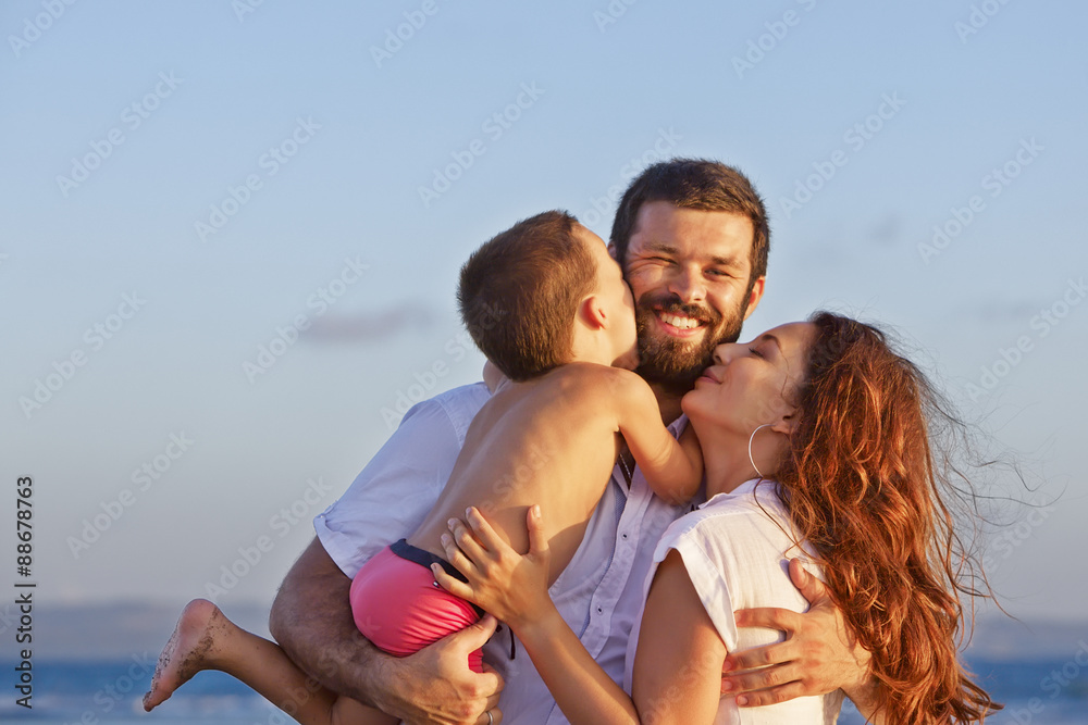 积极家庭的画像——幸福的母亲和父亲双手抱着婴儿儿子，在san上快乐地行走