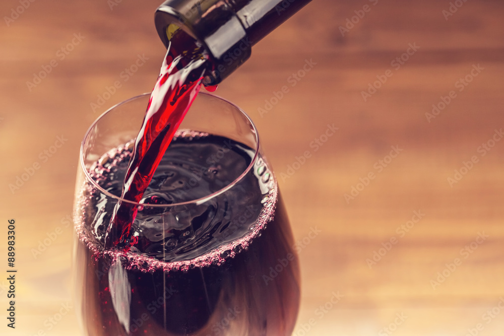 在木制背景下将红酒倒入玻璃杯