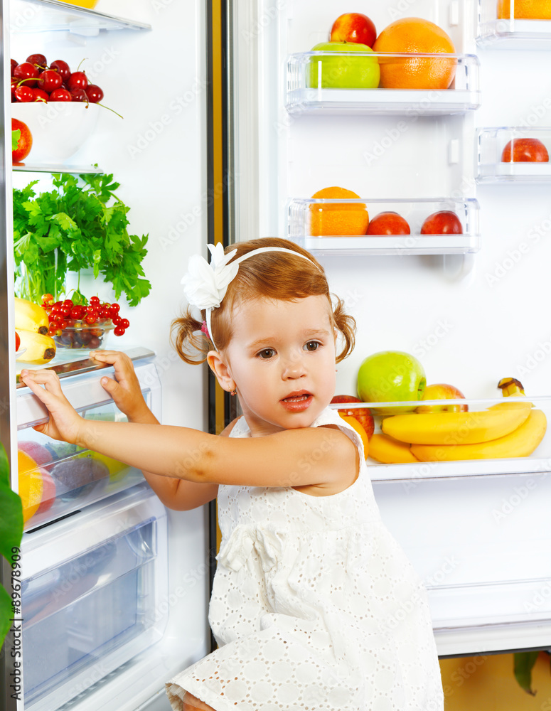 冰箱附近的快乐小女孩，有健康的食物、水果和