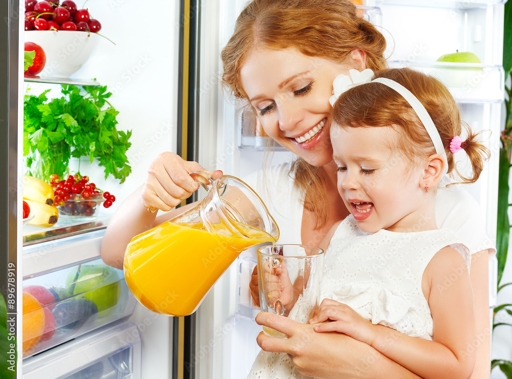 幸福的家庭母亲和婴儿女儿在喝橙汁