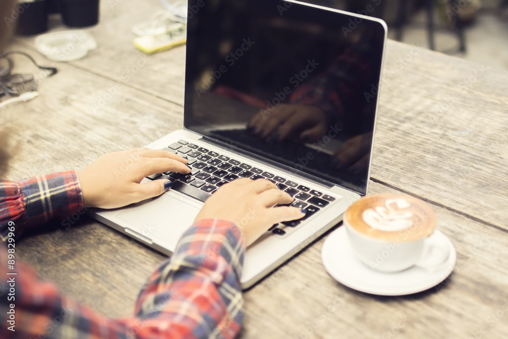 woman typing on a laptop with cup of coffee at morning