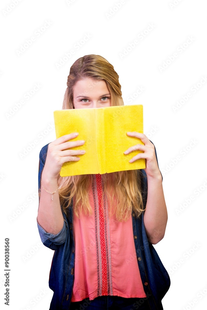 Composite image of student covering face with book in library 