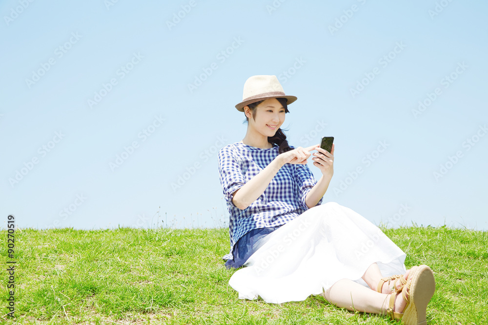丘でスマートフォンを使う女性
