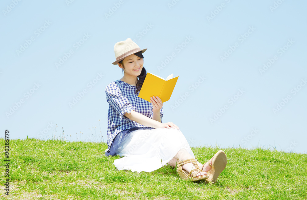 丘で本を読む女性