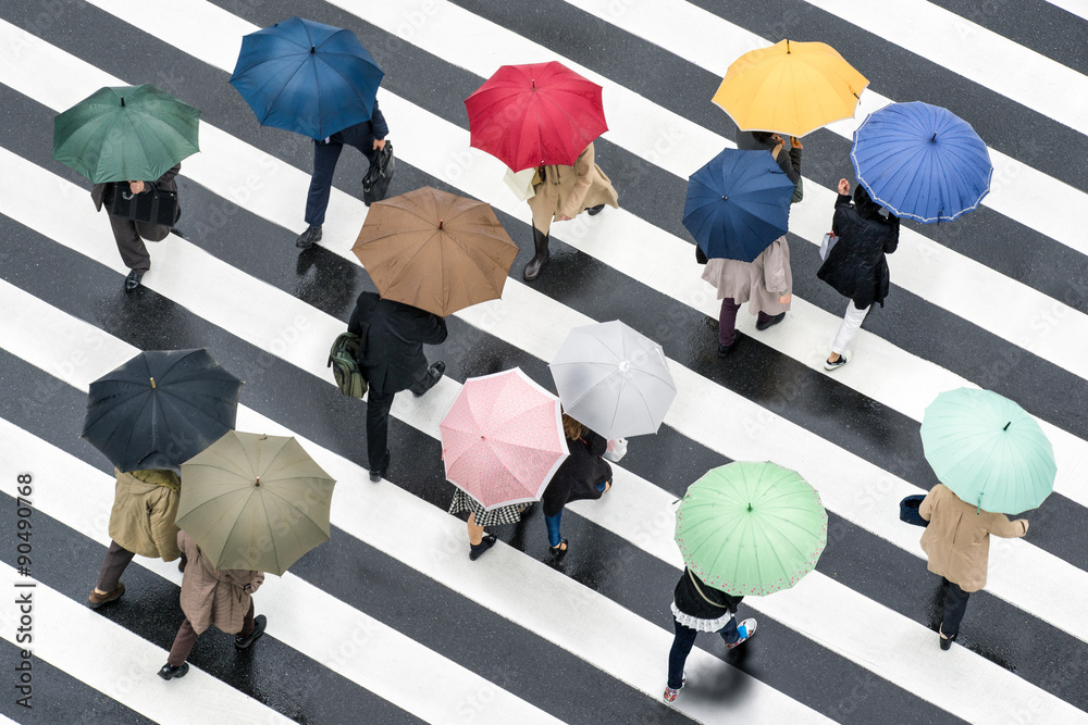 Fußgänger mit Regenschirm auf einer Kreuzung