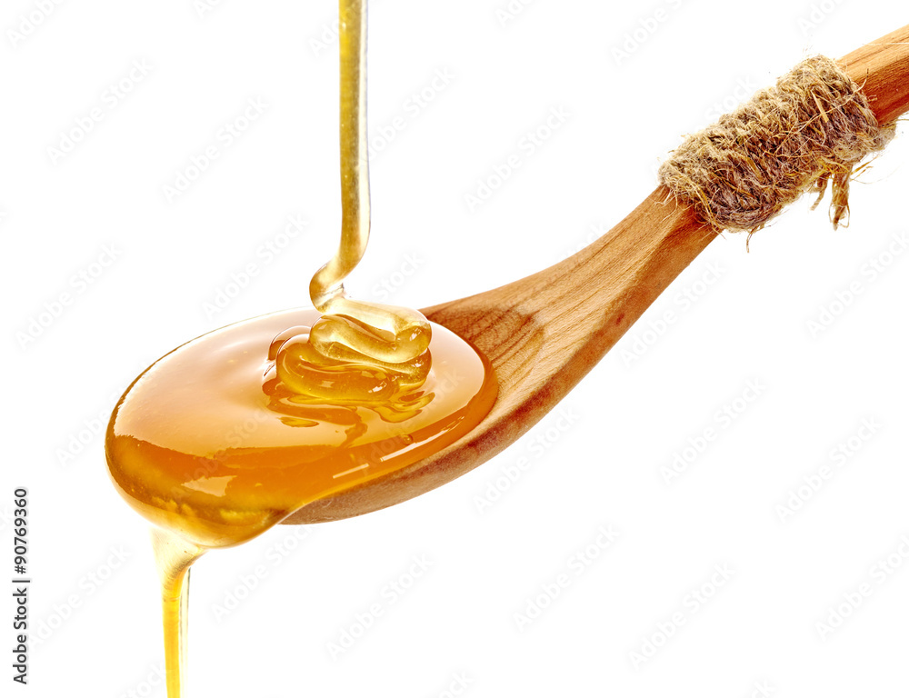 honey pouring into wooden spoon