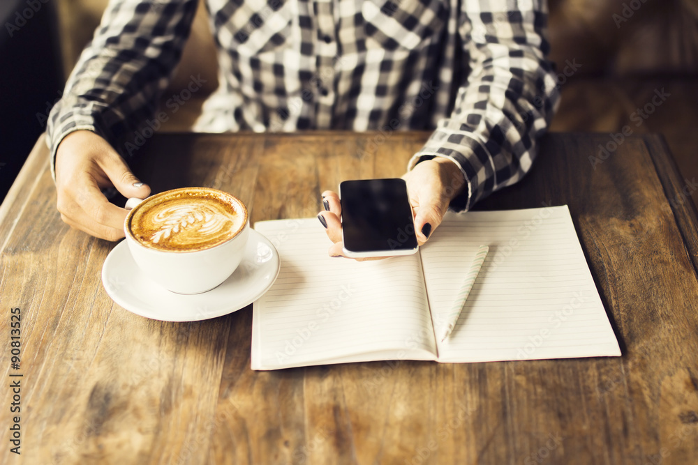 Girl with smartphone, blank diary with pen and cappuccino on a w