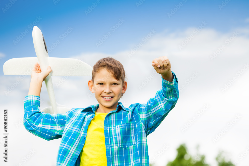 微笑的男孩手持白色飞机玩具的肖像
