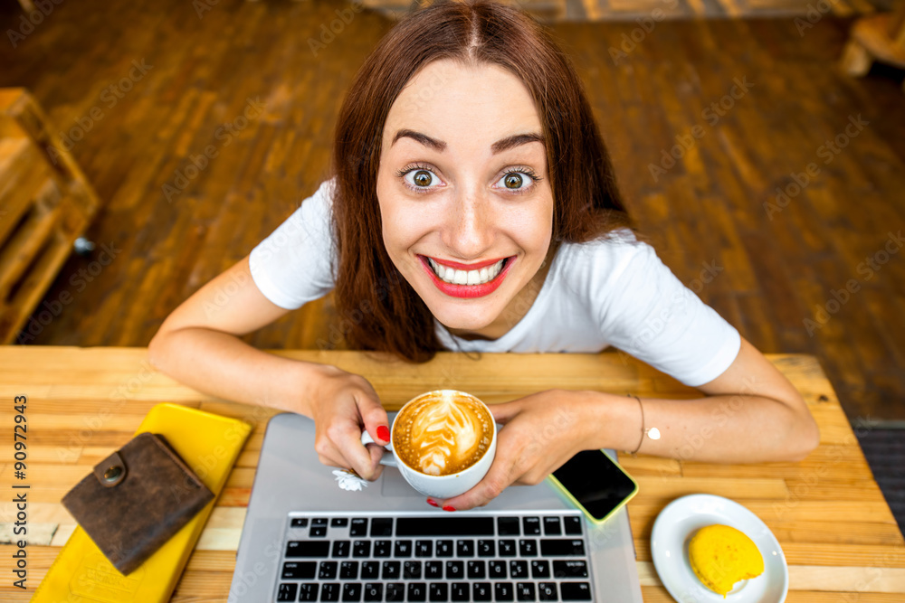 Woman enjoying cappuccino sitting with laptop