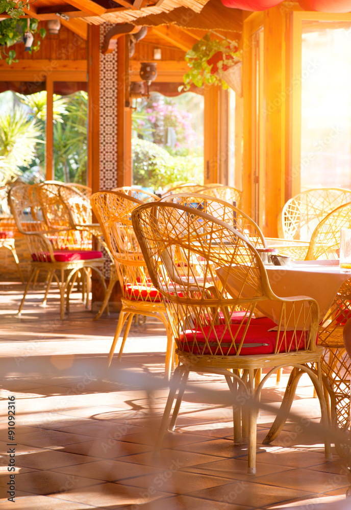 餐厅内部。带桌子和柳条椅的夏季咖啡露台