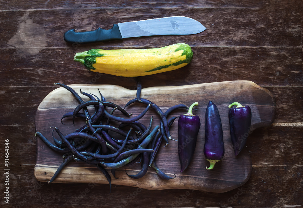 Violet chili peppers, beans and yellow zucchini on rustic wooden