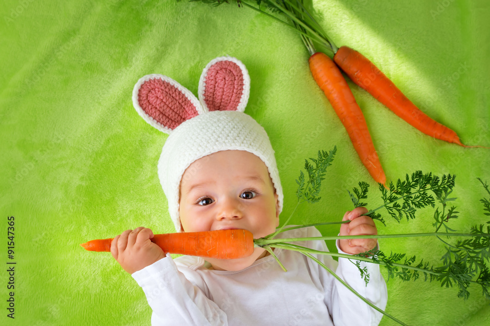 戴着兔子帽的婴儿吃胡萝卜
