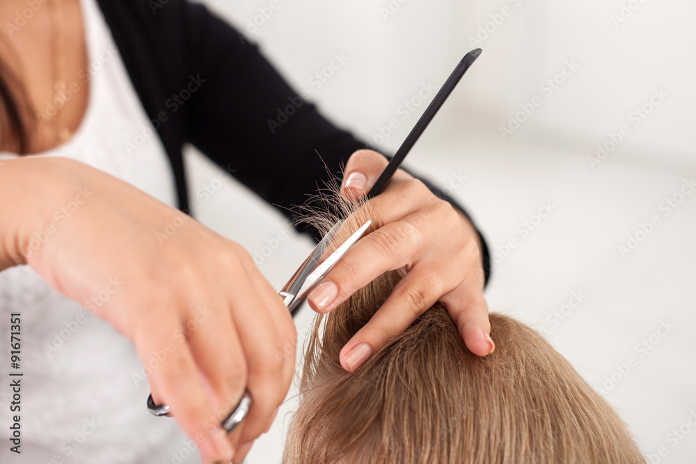 专业年轻发型师正在为男孩理发