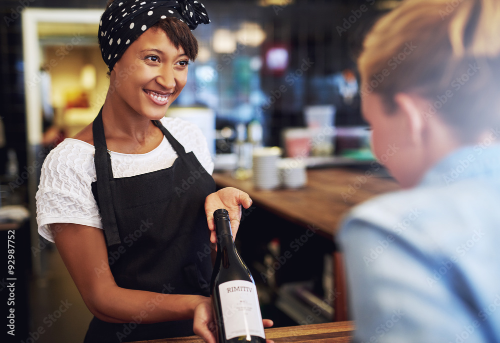 Smiling waitress or bartender showing red wine