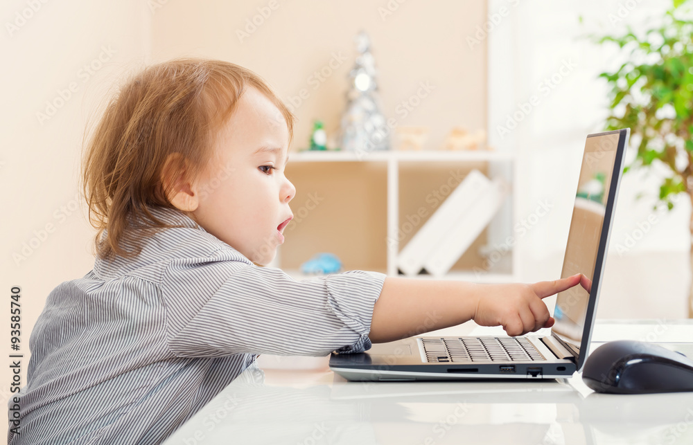 蹒跚学步的女孩指着笔记本电脑屏幕