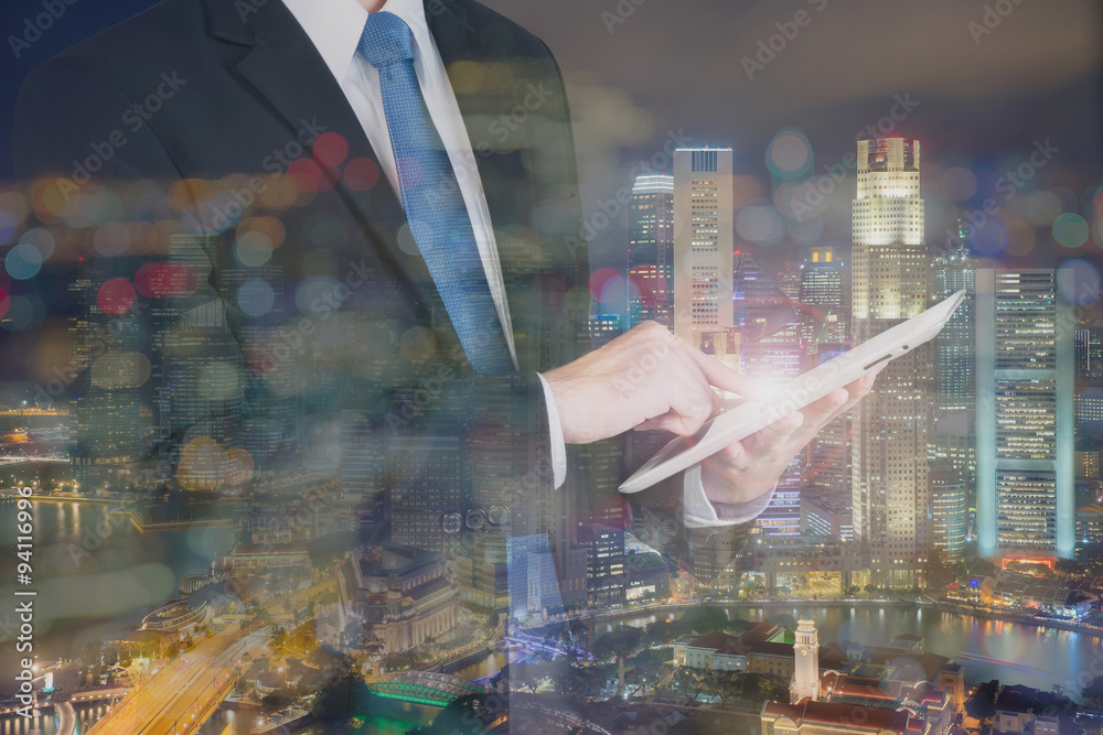 Double exposure of businessman using the tablet with cityscape