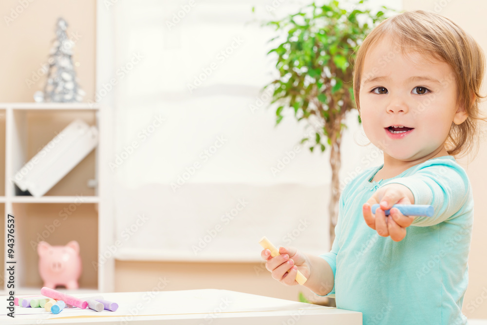 快乐的蹒跚学步的女孩玩粉笔