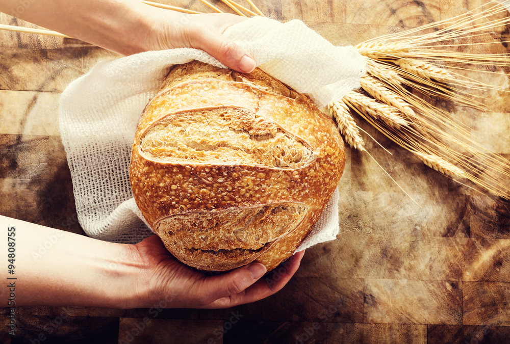 面包师拿着一条面包在乡村的面包上