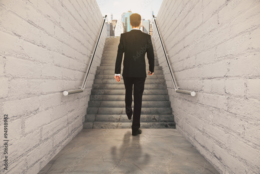Businessman isclimbing up the stairs between brick walls and con