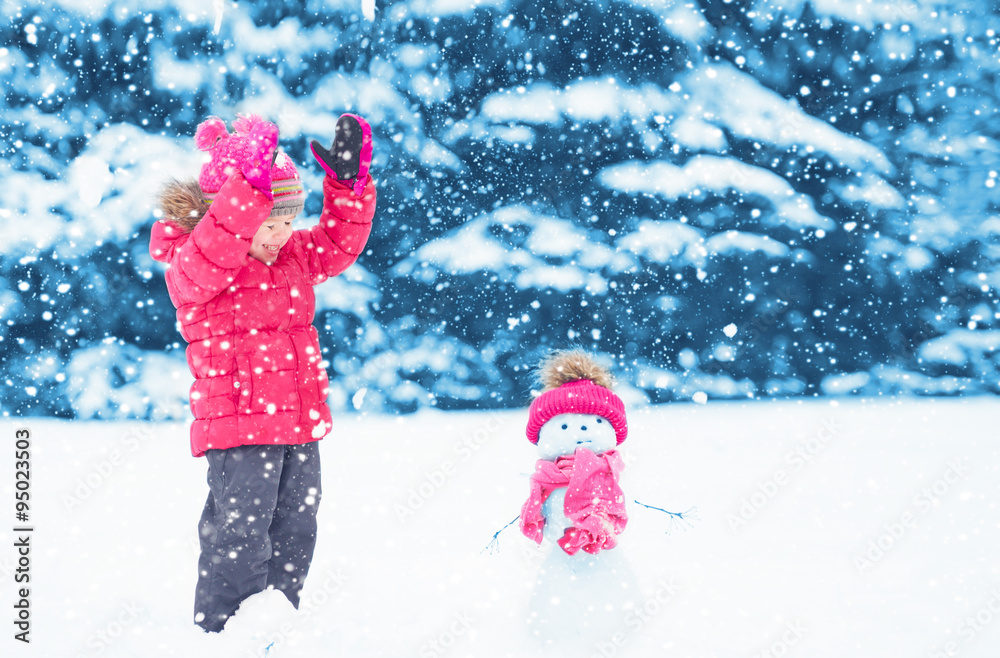 快乐的小女孩和雪人在冬天散步